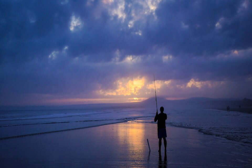 Mann fischt am Strand